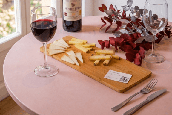 Tabla de quesos variados servida con copa de vino tinto sobre mesa rosa en restaurante de Ruzafa.